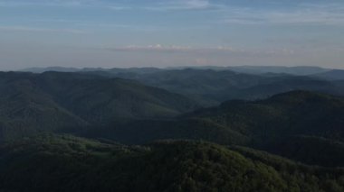 Güzel dağların, mavi gökyüzünün ve yeşil ormanın sabah ya da akşam insansız hava aracı görüntüleri. Vahşi doğada büyük bir orman. Açık hava seyahati konsepti