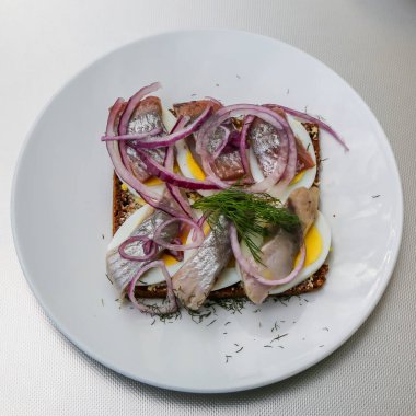 Geleneksel Danimarka sandviçi, ringa balığı, yumurta, salatalık ve soğanlı.