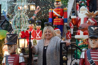 BrooKLYN, New York - 14 Aralık 2023: Lucy Spata, Brooklyn 'in Dyker Heights semtindeki Noel evi dekorasyonunun önünde. 1986 'da Dyker Heights' taki dekorasyon trendine öncülük etti.