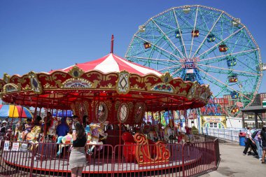 BrooKLYN, New York - 13 Nisan 2023: Çocuklar ve yetişkinler, Brooklyn, New York 'taki Coney Island Boardwalk' taki Luna Park 'ta geleneksel bir panayır Coney Island atlıkarıncasına biniyorlar