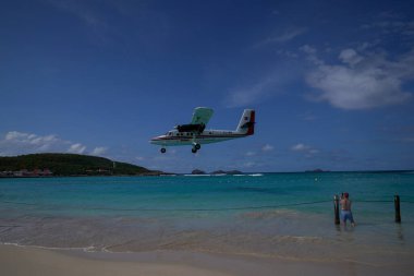 St. Barts, FRENCH Batı INDIES - 18 Nisan 2024: Winair De Havilland Kanada DHC-6-300 Twin Otter uçağı Remy de Haenen Havalimanı 'na inmek üzere inmiştir. 2,133 feet yüksekliğindeki pisti dünyanın en kısa pistlerinden biridir..