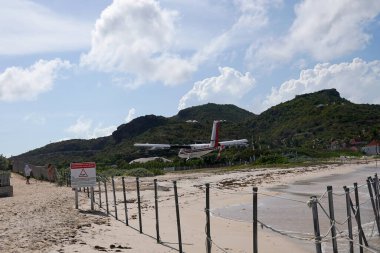 St. Barts, FRENCH Batı INDIES - 18 Nisan 2024: Winair De Havilland Kanada DHC-6-300 Twin Otter uçağı Remy de Haenen Havalimanı 'na inmek üzere inmiştir. 2,133 feet yüksekliğindeki pisti dünyanın en kısa pistlerinden biridir..