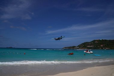ST. BARTS, FRENCH WEST INDIES - APRIL 18, 2024: Winair De Havilland Canada DHC-6-300 Twin Otter plane descends for landing at Remy de Haenen Airport also known as Saint Barthelemy Airport. At 2,133 ft its runway is one of the shortest in the world. clipart