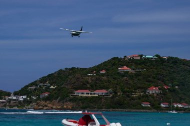 BARTS, FRENCH BEST INDIES - 18 Nisan 2024: St Barth Commuter Cessna 208B Grand Caravan uçağı, Saint Barthelemy Havaalanı olarak da bilinen Remy de Haenen Havalimanı 'na inmek için inmiştir. 2,133 feet yüksekliğindeki pisti dünyanın en kısa pistlerinden biridir..