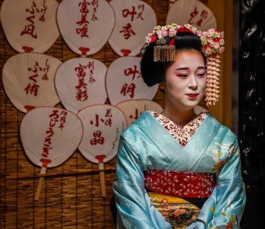 KYOTO, JAPONYA - 8 Ekim 2024: Gion ilçesinde çay seremonisi sırasında Maiko çırağı. Maiko bir çırak geyşa. Maikos ozashiki 'deki ziyaretçiler için şarkı söylüyor, shamisen çalıyor veya enstrümanlar çalıyor.