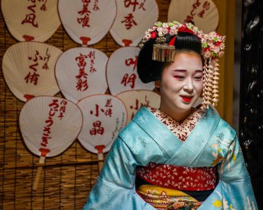 KYOTO, JAPONYA - 8 Ekim 2024: Gion ilçesinde çay seremonisi sırasında Maiko çırağı. Maiko bir çırak geyşa. Maikos ozashiki 'deki ziyaretçiler için şarkı söylüyor, shamisen çalıyor veya enstrümanlar çalıyor.