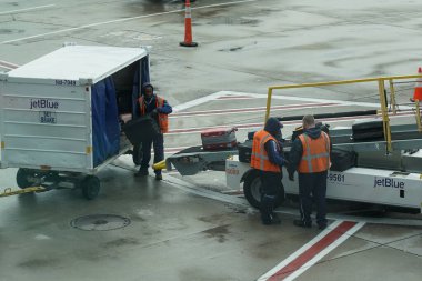 NEW YORK - 31 Mayıs 2021: JetBlue bagaj taşıyıcıları New York 'taki John F. Kennedy Uluslararası Havaalanı' nda piste bagaj yükleme