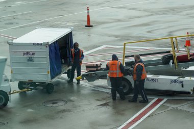 NEW YORK - 31 Mayıs 2021: JetBlue bagaj taşıyıcıları New York 'taki John F. Kennedy Uluslararası Havaalanı' nda piste bagaj yükleme