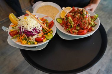 Geleneksel Türk salataları ve garsonun servis ettiği humus