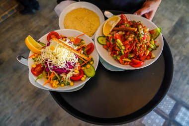 Geleneksel Türk salataları ve garsonun servis ettiği humus