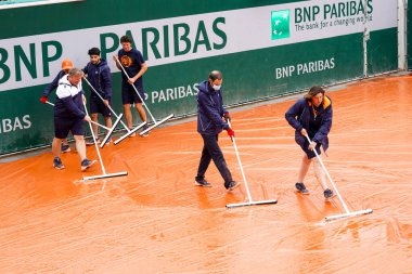 PARIS, FRANCE - MAY 28, 2024: Court attendants sweep the water off the tarpaulin-covered outside court after a rainfall during the 2024 Roland Garros at the Stade Roland Garros in Paris, France clipart