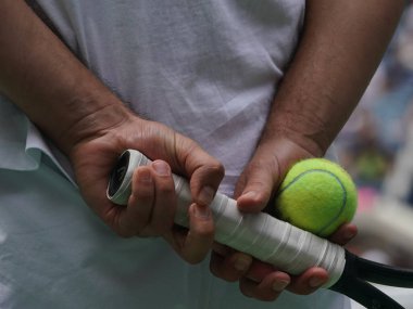 Tenis oyuncusu raket ve tenis topu tutuyor