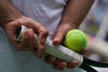 Tenis oyuncusu raket ve tenis topu tutuyor