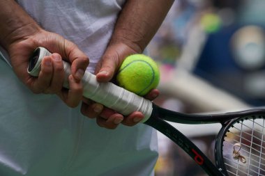 Tenis oyuncusu raket ve tenis topu tutuyor