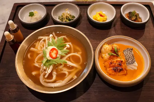 Istakoz kalguksu, gochujang boullabaisse, kimchi ve sebze turşusu Kore restoranında servis edilir. Kalguksu ev yapımı, buğday unlu erişteli Kore eriştesidir.