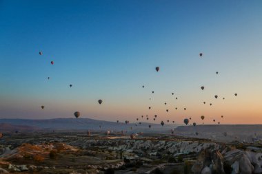 Kapadokya, Türkiye 'deki sıcak hava balonları filosunun güneş doğarken görüntüsü. Kapadokya popüler bir turizm merkezidir..