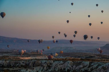 Kapadokya, Türkiye 'deki sıcak hava balonları filosunun güneş doğarken görüntüsü. Kapadokya popüler bir turizm merkezidir..
