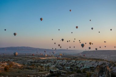 Kapadokya, Türkiye 'deki sıcak hava balonları filosunun güneş doğarken görüntüsü. Kapadokya popüler bir turizm merkezidir..