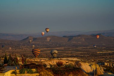Kapadokya, Türkiye 'deki sıcak hava balonları filosunun güneş doğarken görüntüsü. Kapadokya popüler bir turizm merkezidir..