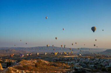 Kapadokya, Türkiye 'deki sıcak hava balonları filosunun güneş doğarken görüntüsü. Kapadokya popüler bir turizm merkezidir..