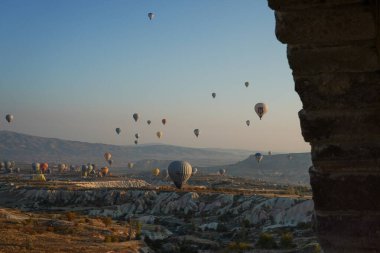 Kapadokya, Türkiye 'deki sıcak hava balonları filosunun güneş doğarken görüntüsü. Kapadokya popüler bir turizm merkezidir..