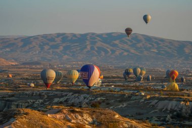 Kapadokya, Türkiye 'deki sıcak hava balonları filosunun güneş doğarken görüntüsü. Kapadokya popüler bir turizm merkezidir..
