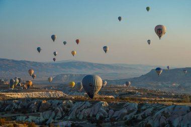 Kapadokya, Türkiye 'deki sıcak hava balonları filosunun güneş doğarken görüntüsü. Kapadokya popüler bir turizm merkezidir..