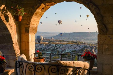 Kapadokya, Türkiye 'deki sıcak hava balonları filosunun güneş doğarken görüntüsü. Lüks otelin manzarası. Kapadokya popüler bir turizm merkezidir..