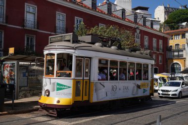LISBON, PORTUGAL - 15 Eylül 2023: Lizbon Alfama Mahallesi 'ndeki Tram 28. Şehrin en ikonik tramvay yolculuğu. Pirinç düğmeleri ve cilalanmış ahşap iç döşemeler gibi orijinal 1930 'lu yıllarda kullanılan klasik sarı tramvaylar.