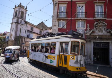 LISBON, PORTUGAL - 15 Eylül 2023: Lizbon Alfama Mahallesi 'ndeki Tram 28. Şehrin en ikonik tramvay yolculuğu. Pirinç düğmeleri ve cilalanmış ahşap iç döşemeler gibi orijinal 1930 'lu yıllarda kullanılan klasik sarı tramvaylar.
