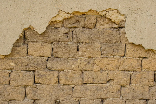 The clay walls of the house from adobe. Erosion of buildings, destroyed masonry, damaged plaster.