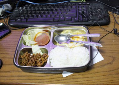 Eating at work place with lunch box in front of computer