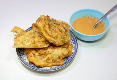 Beyaz arka planda sebze ve fıstık sosuyla dolu kızarmış bakwan.