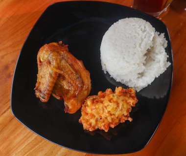 Tahta masada servis edilen kızarmış tavuklu pilav ve mısır böreği..