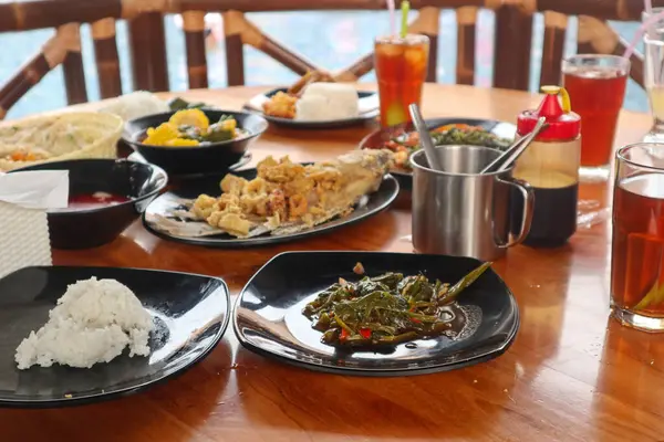 Sundanese Restaurant Menu, West Java, Indonesia. sour vegetables, fried gurami, kale and rice. On wooden table.