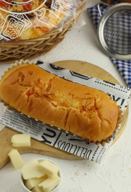 Tahta tabakta peynir aromalı ekmek üzerine peynir serpiştirilmiş ekmek.