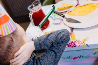 Doğum günü partisi aksesuarlı çocuk masada tek başına eğleniyor.