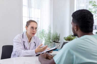 Doktor listeyi tutuyor ve hastanedeki hasta adamla konuşuyor. Doktor, erkek hastayı hastane odasında muayene ediyor..