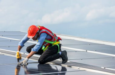 Çatıda çalışan mühendis güneş paneli kuruyor. Mühendis ya da işçi iş binasının çatısındaki güneş panelleri ya da güneş pilleri üzerinde çalışır.