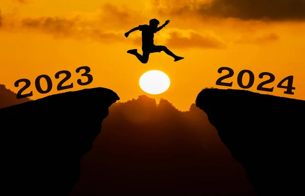 2023年至2024年间 一个年轻人跳过太阳 穿过山丘轮廓的缝隙 看到了夜晚五彩斑斓的天空 新年快乐2023 — 图库照片