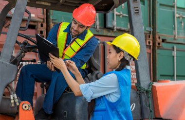 Ustabaşı konteyner kargo limanında konteynırları yüklemeye çalışıyor. Konteyner kargo alanında çalışan profesyonel ustabaşı konteynırdaki malları kontrol ediyor. İşçiler konteynırları kontrol için açıyorlar.