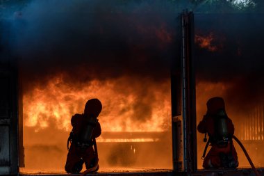 Firefighter Concept. Fireman using water and extinguisher to fighting with fire flame. firefighters fighting a fire with a hose and water during a firefighting training exercise