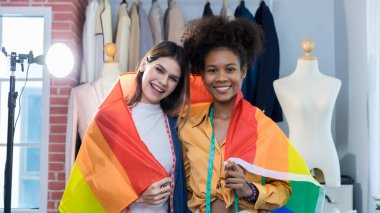 Gururlu gökkuşağı bayrağıyla ayakta duran mutlu kadınlar.