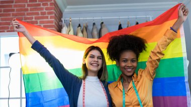 Gururlu gökkuşağı bayrağıyla ayakta duran mutlu kadınlar.