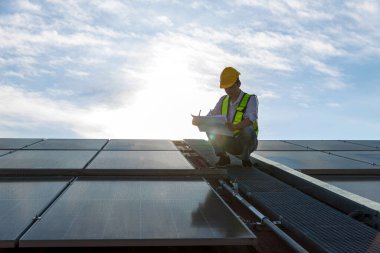 Çatıda çalışan mühendis güneş paneli kuruyor. Mühendis ya da işçi iş binasının çatısındaki güneş panelleri ya da güneş pilleri üzerinde çalışır.