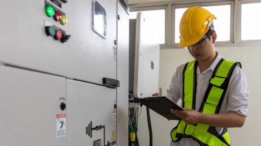 Electrical engineer working in control room. Electrical engineer man checking Power Distribution Cabinet in the control room clipart