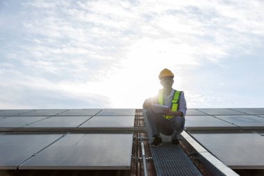 Çatıda çalışan mühendis güneş paneli kuruyor. Mühendis ya da işçi iş binasının çatısındaki güneş panelleri ya da güneş pilleri üzerinde çalışır.