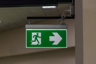Kaçış yolunu gösteren yeşil acil çıkış işareti. Binadaki yangın çıkışı..