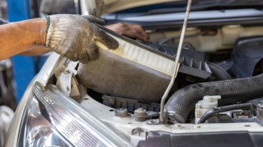 Tamirci hava filtresini kontrol edip değiştiriyor. Tamirci tamirhanedeki hava filtresini kontrol ediyor..