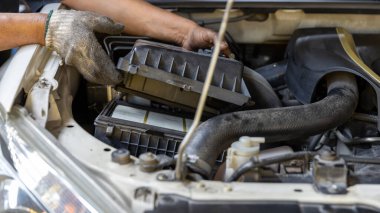 Tamirci hava filtresini kontrol edip değiştiriyor. Tamirci tamirhanedeki hava filtresini kontrol ediyor..